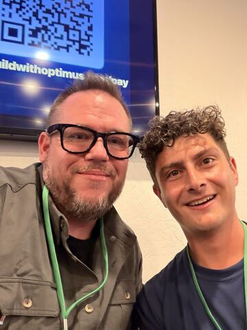 JJ and a guest at a conference, an event screen behind them