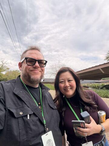 JJ and a guest outdoors, both wearing conference lanyards